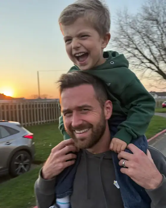 Vater mit Sohn auf den Schultern am Abend