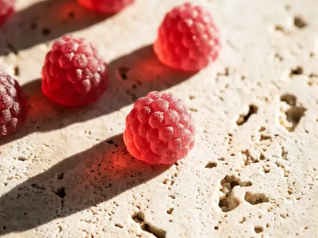 Himbeer-Gummies in Himbeerform auf hellem Stein